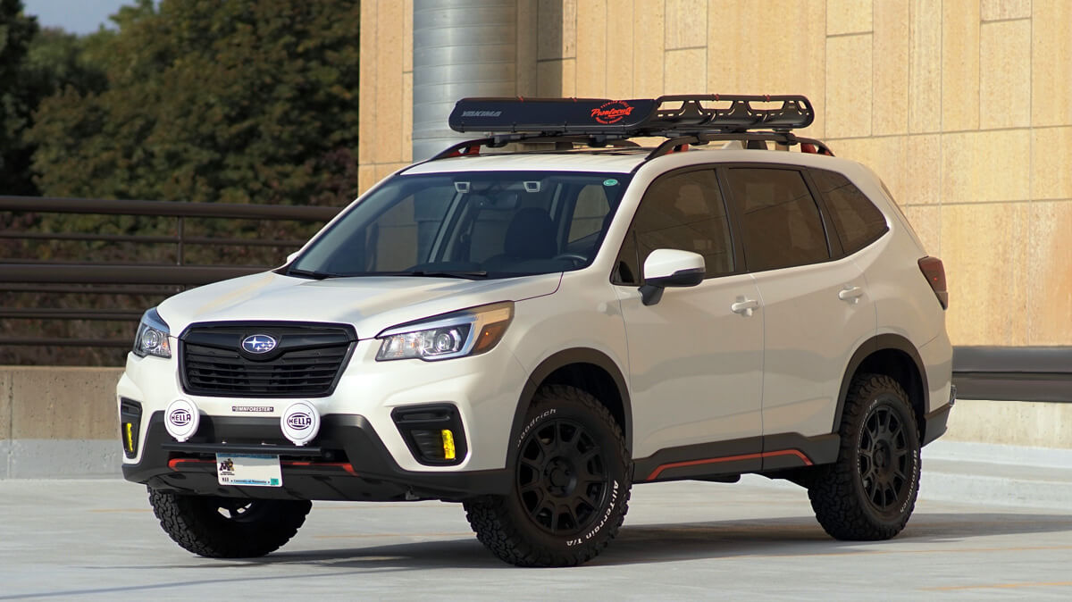 Czerwony Subaru Forester wspina się po skalistym terenie z oponami Mud-Terrain