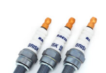 Świece zapłonowe w silniku turbo – kiedy wymiana jest konieczna i jak często ją planować? Mechanik pod otwartą maską samochodu wymienia świece w silniku turbo