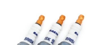 Świece zapłonowe w silniku turbo – kiedy wymiana jest konieczna i jak często ją planować? Mechanik pod otwartą maską samochodu wymienia świece w silniku turbo