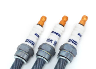 Świece zapłonowe w silniku turbo – kiedy wymiana jest konieczna i jak często ją planować? Mechanik pod otwartą maską samochodu wymienia świece w silniku turbo