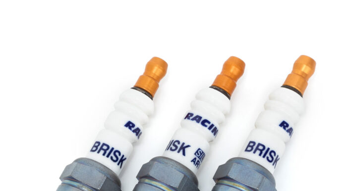 Świece zapłonowe w silniku turbo – kiedy wymiana jest konieczna i jak często ją planować? Mechanik pod otwartą maską samochodu wymienia świece w silniku turbo