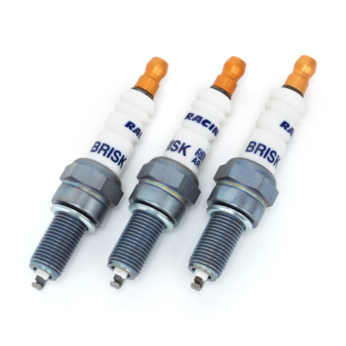 Mechanik pod otwartą maską samochodu wymienia świece w silniku turbo